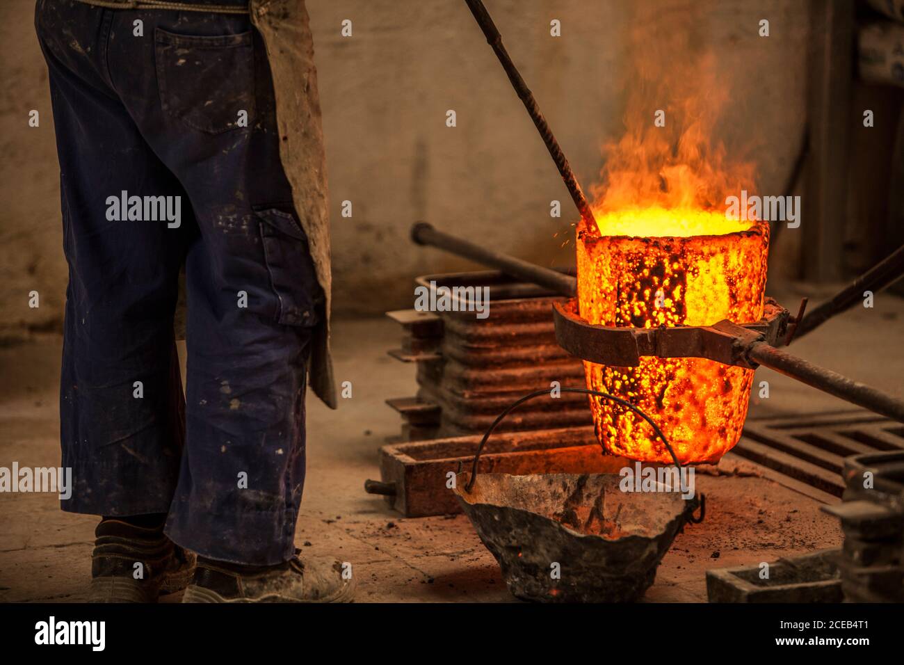 Vue rognée de l'homme dans les vêtements de travail debout et empêchant fours à charbon avec feu Banque D'Images