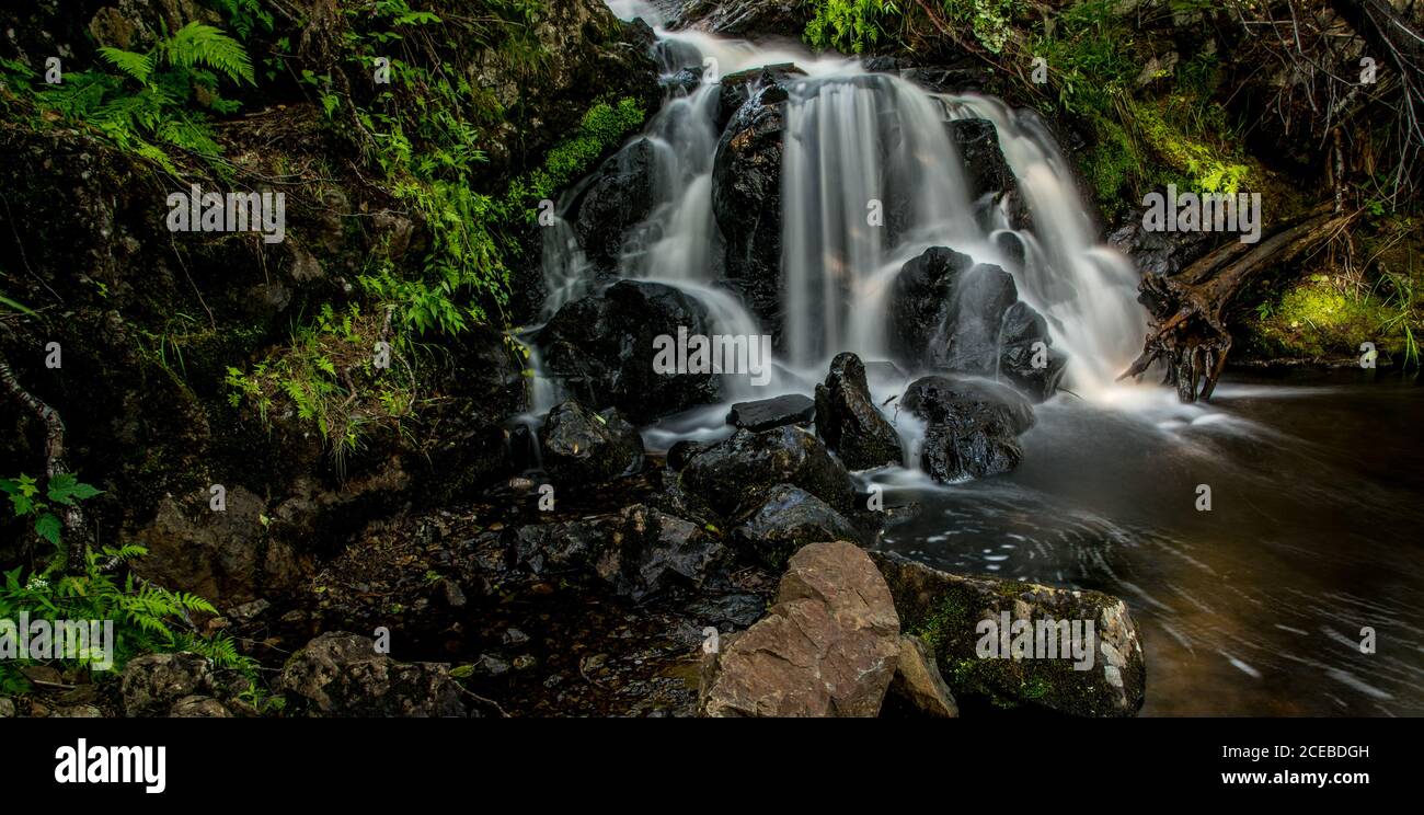 Cascades de Moody avec des feuilles vertes et des pierres noires, longue exposition Banque D'Images