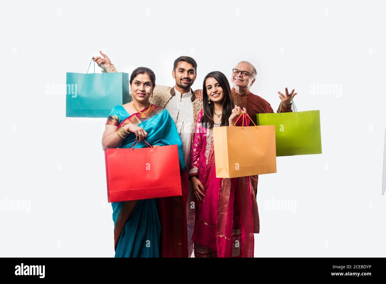 Joyeux shopping familial indien pour le festival ou le mariage de Diwali, montrant des sacs de papier colorés, isolés sur blanc Banque D'Images