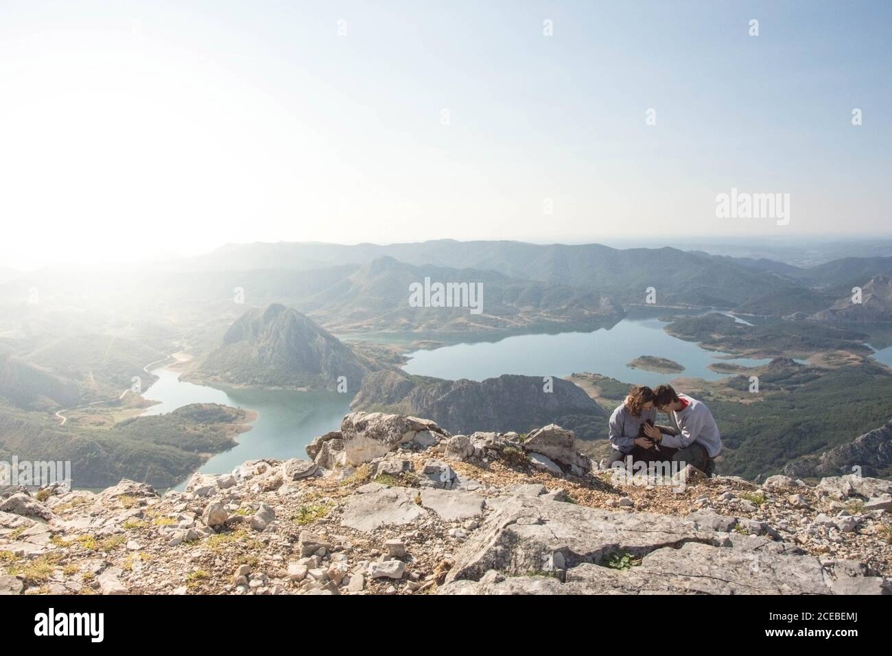 Un jeune homme et une jeune femme qui pettent un petit chien assis au sommet d'un rocher brut, par une incroyable journée ensoleillée en Espagne Banque D'Images