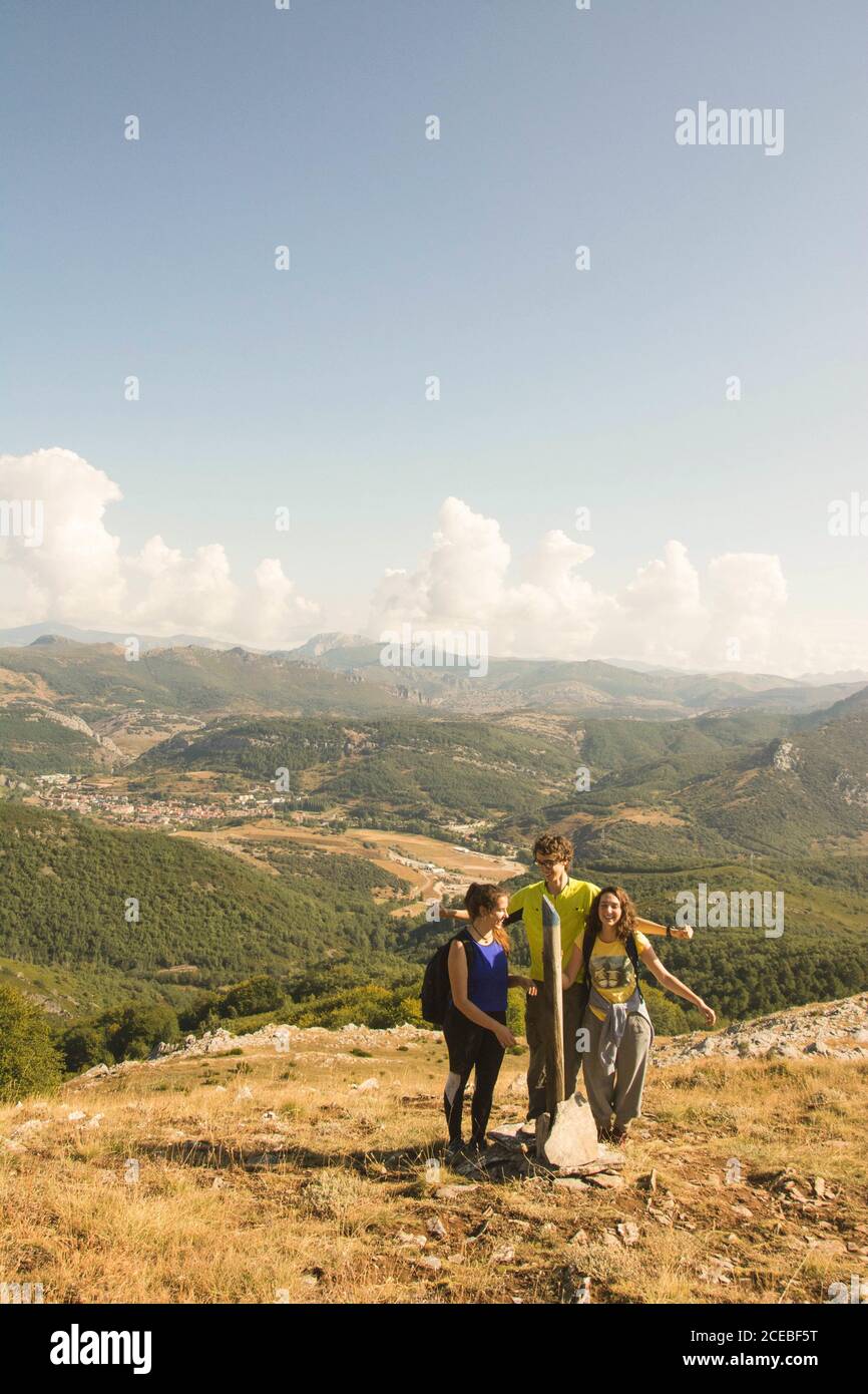 Jeune homme et deux femmes debout sur la colline sur fond de belle nature le jour nuageux Banque D'Images