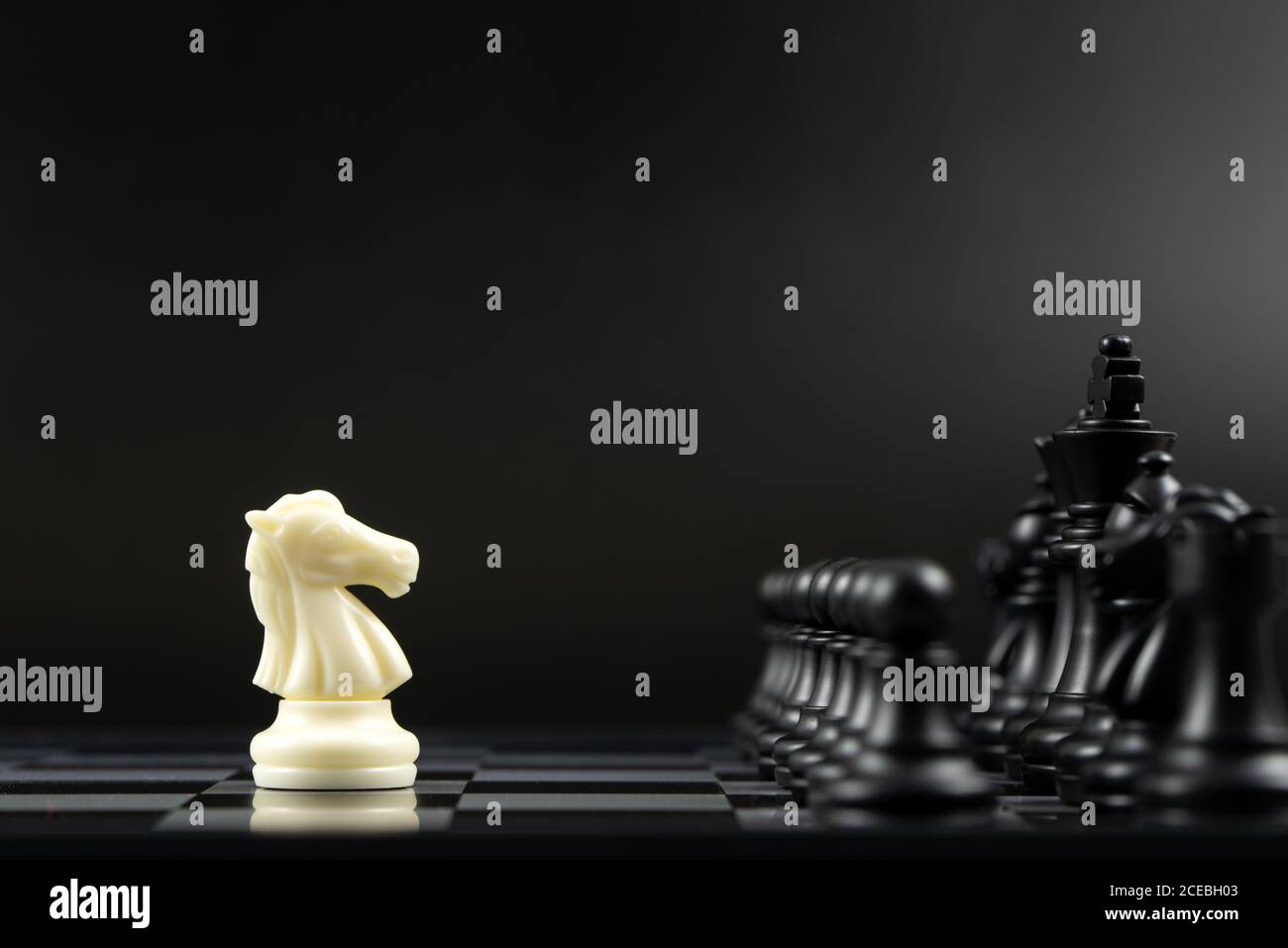 Pièce d'échecs blanche contre toutes les pièces d'échecs noires Banque D'Images