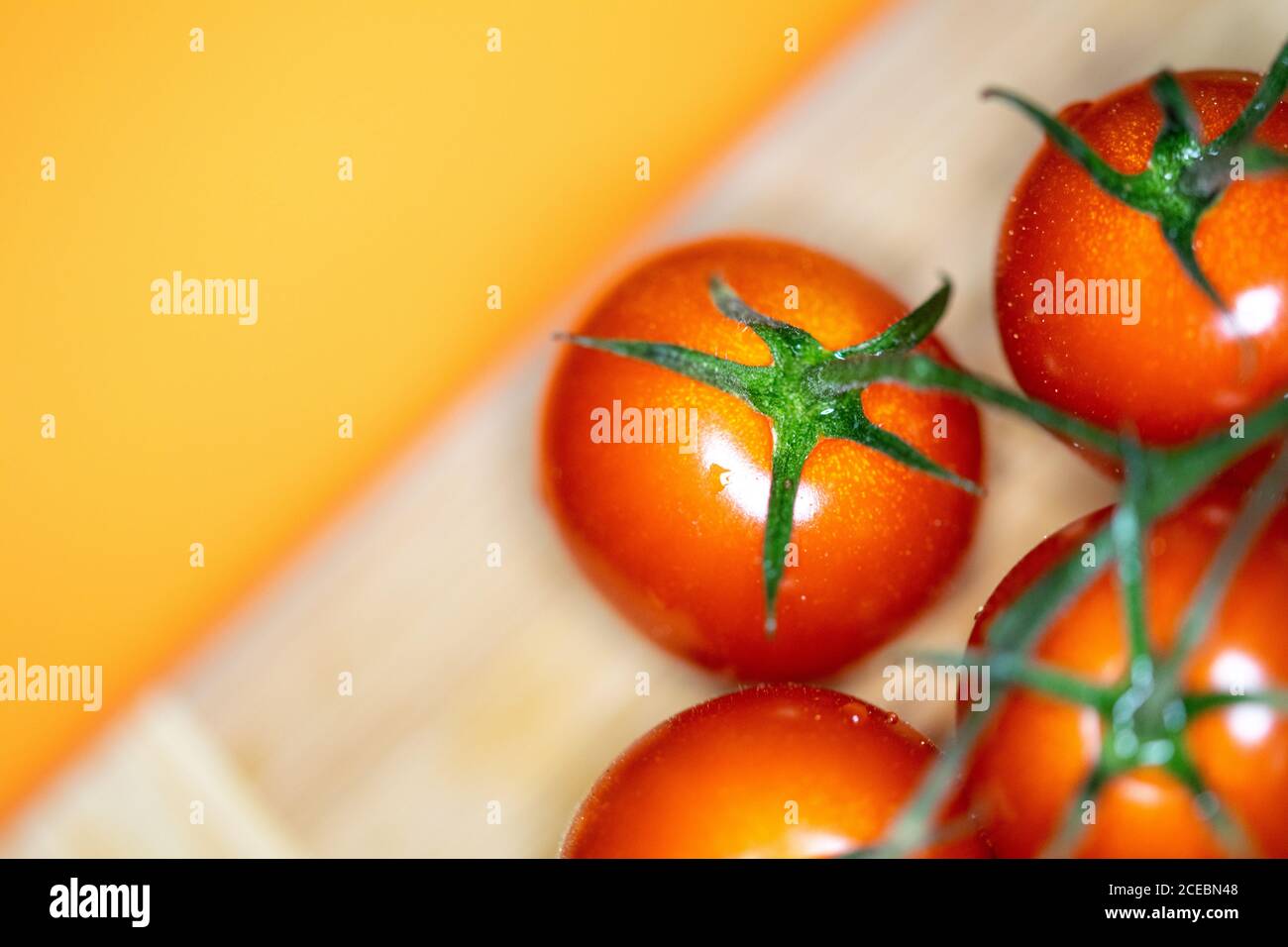 un bouquet de tomates cerises sur une planche à découper avec un arrière-plan jaune Banque D'Images