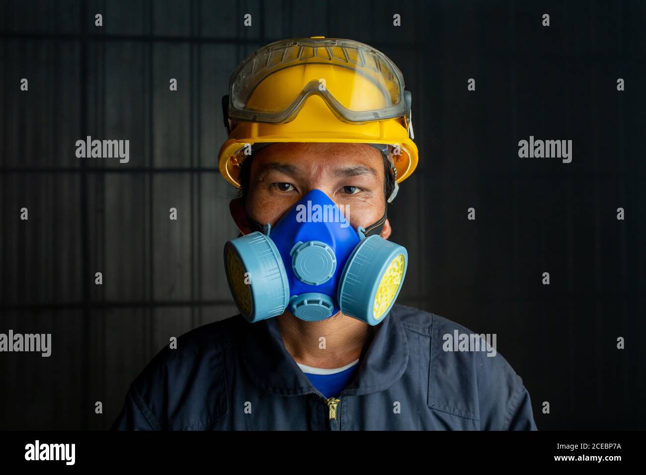 Les vêtements de travail asiatiques portent un respirateur dans une atmosphère toxique et fumée. L'image montre l'importance de la préparation à la protection et de la sécurité dans les usines industrielles Banque D'Images