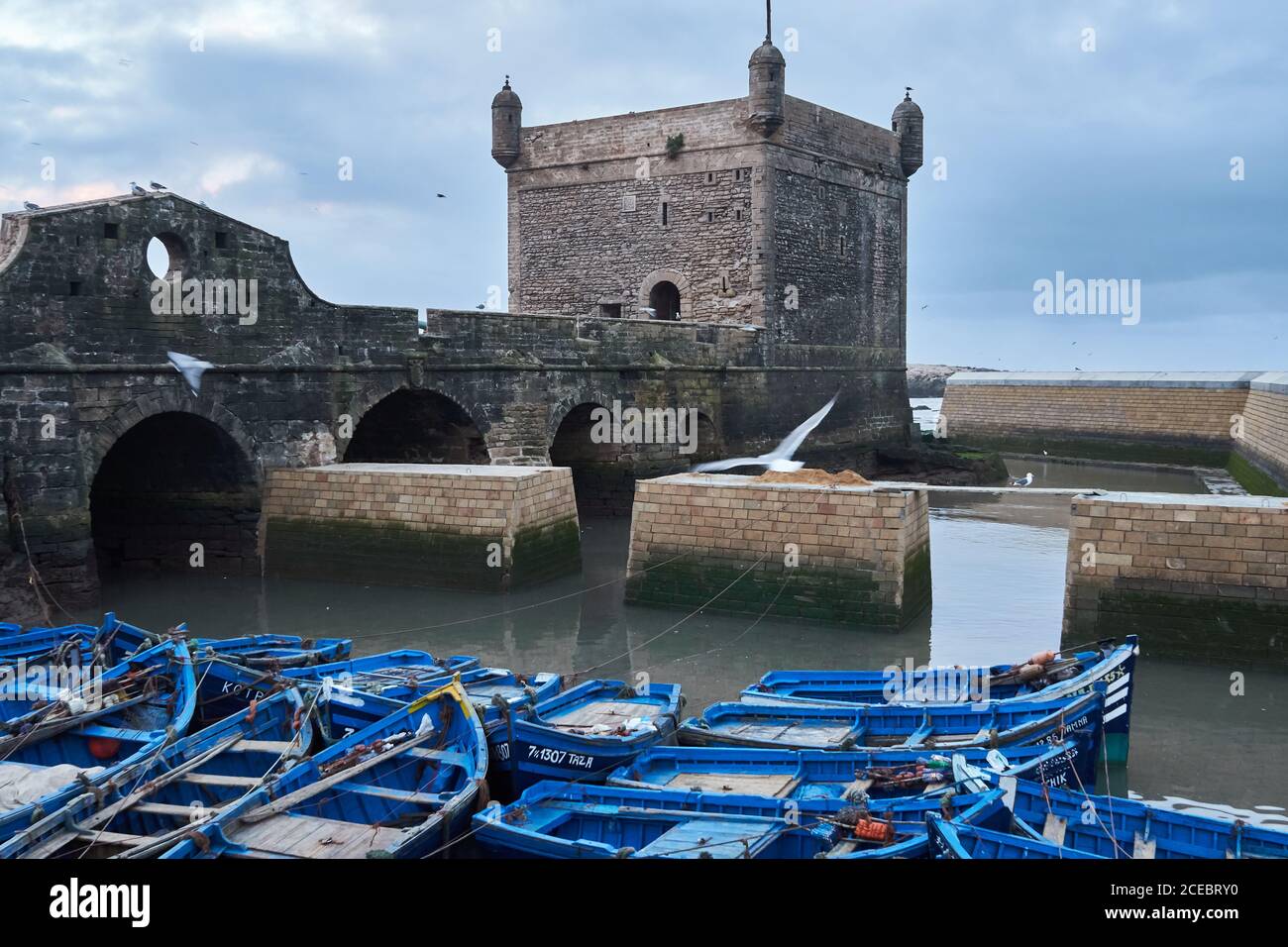 Pêche bleu bateaux amarrés à la construction historique à Essaouira, Maroc Banque D'Images