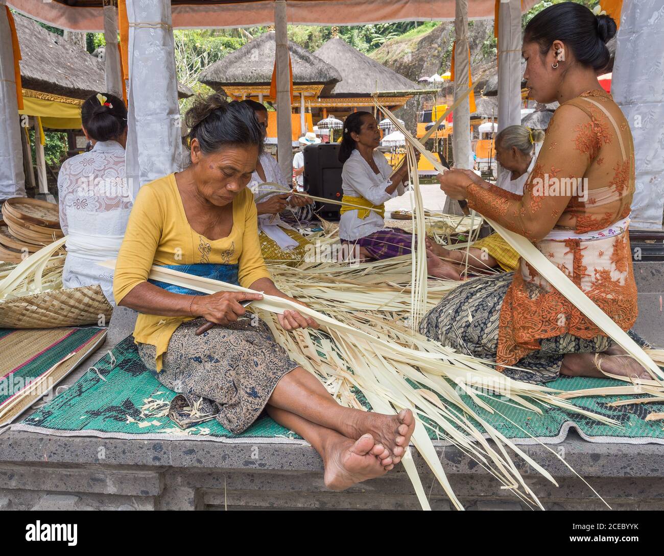 Île Sulawesi, Indonésie - août 15 2015 : groupe de femelles asiatiques assis sur des nattes et trancher des feuilles de palmier séchées dans un petit village en Indonésie Banque D'Images