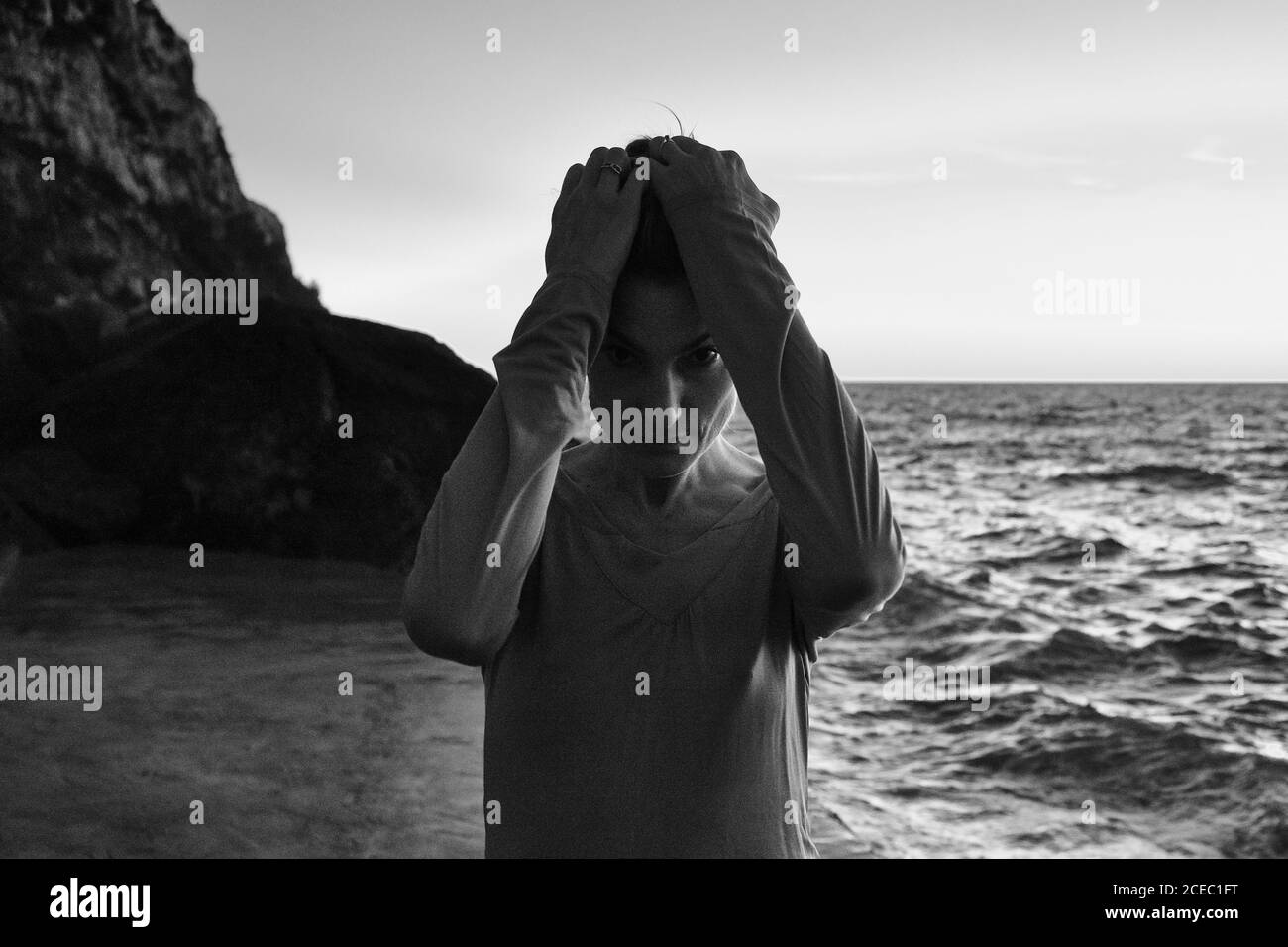 Belle femme stressée gardant les mains sur la tête tout en restant debout rive près de la mer Banque D'Images