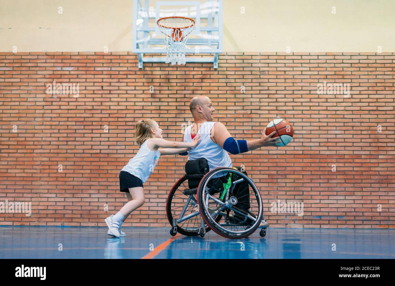 Les hommes handicapés et la petite fille en action tout en jouant basket-ball intérieur Banque D'Images