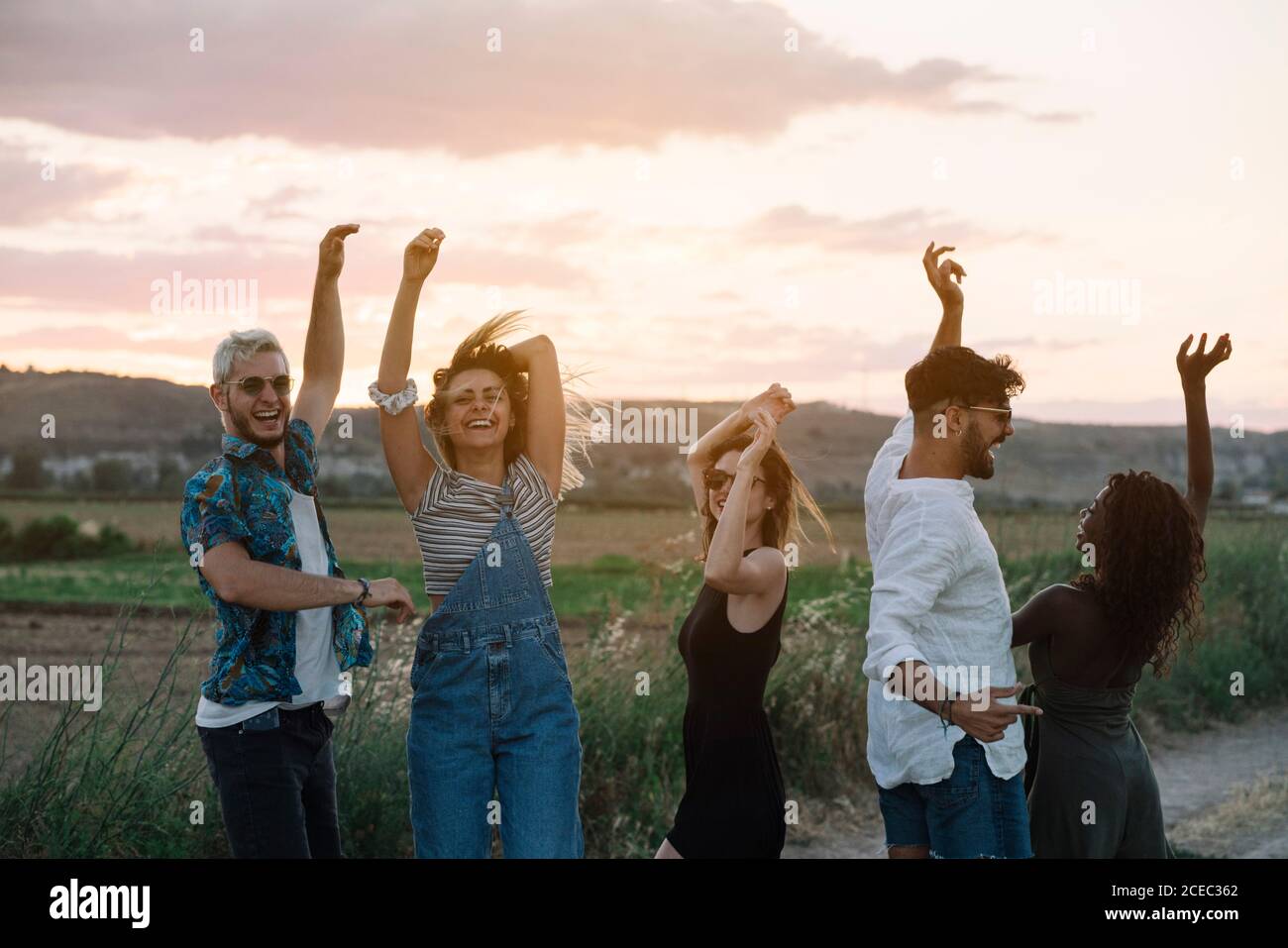 Groupe de jeunes en tenues décontractées riant et dansant tout en s'amusant dans la belle campagne ensemble Banque D'Images