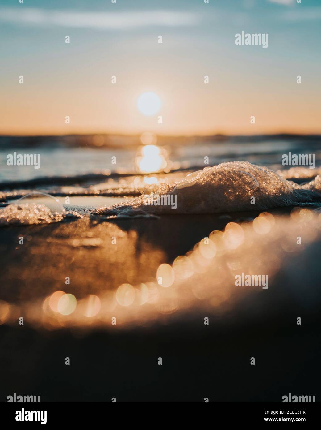 Gros plan sur la fonte des morceaux de glace sur la rive et l'eau dans les lumières du coucher du soleil. Banque D'Images