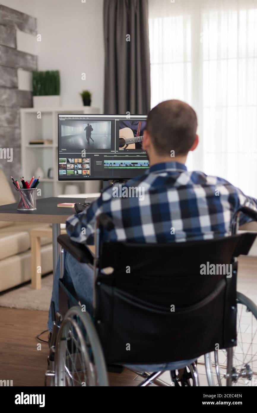 Vidéaste avec handicap assis sur un fauteuil roulant effectuant le calibrage des couleurs sur film. Inadmissible réalisateur qui fait ses affaires en ligne, utilisant la haute technologie, assis dans son appartement, travaillant à distance dans des conditions spéciales. Banque D'Images