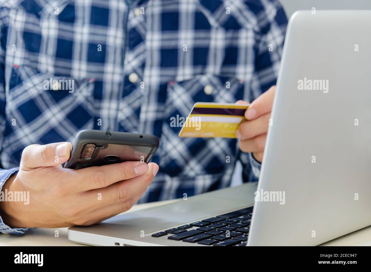 Man Shopping en ligne à l'aide d'un ordinateur portable avec une carte de crédit.mains tenant une carte de crédit et un smartphone. Banque D'Images