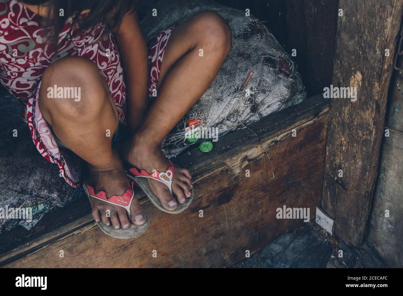 Récolte de dessus de la pauvre petite fille assis dessus matelas abîmé en  mauvais état sur un lit en bois Photo Stock - Alamy
