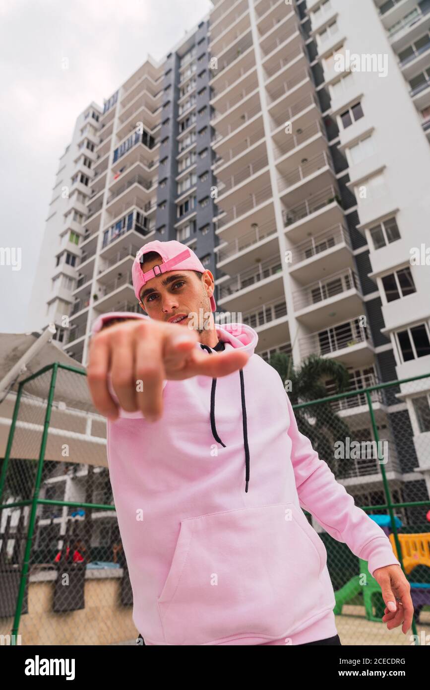 Beau jeune homme dans un élégant bois rose pointant vers la caméra en position debout sur un terrain de sport Banque D'Images