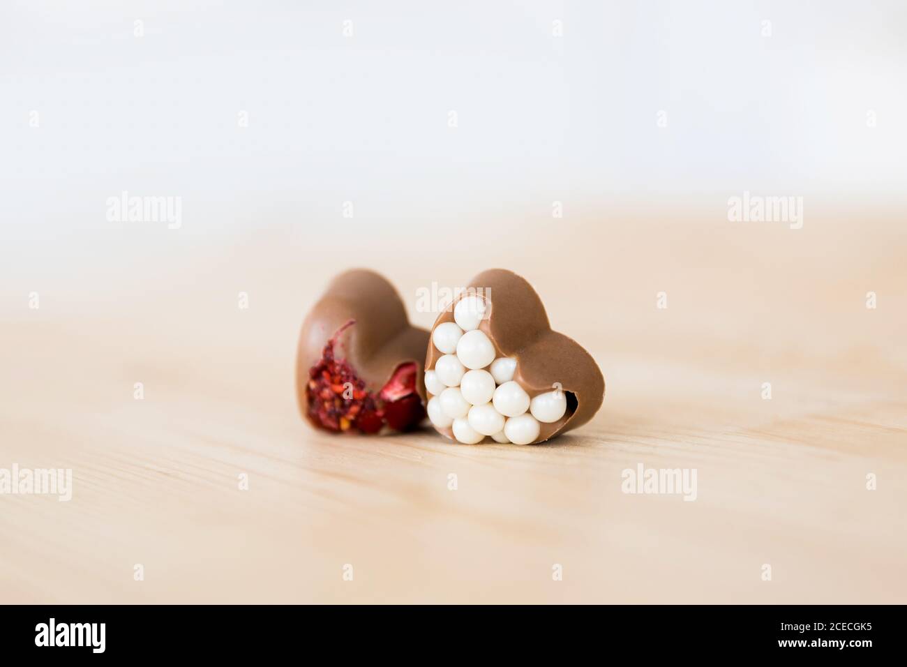 Chocolats artisanaux belges en forme de cœur avec garniture rouge et blanche couchez-vous sur une table en bois Banque D'Images