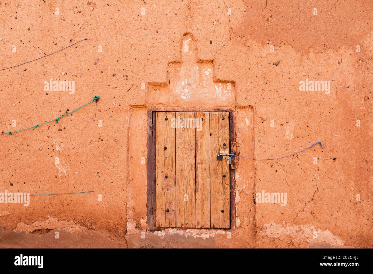 Fenêtre en bois fermée dans une maison marocaine traditionnelle avec mur de couleur rouge terre cuite. Texture de sorbrée, arrière-plan. Style arabe dans l'architecture. Banque D'Images