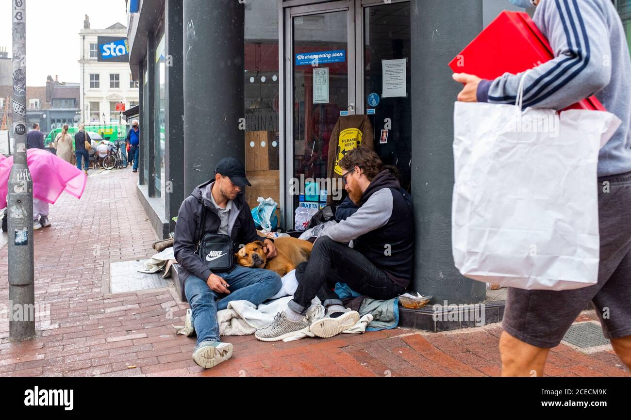 Les hommes se sont assis à l'entrée de la boutique de voyages fermée de STA Au coin de Ship Street et North Street Brighton avec Chien Royaume-Uni Banque D'Images