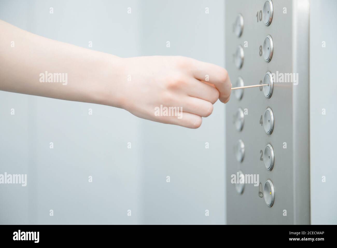 Femme appuie sur le bouton de l'ascenseur avec balayage. Concept de désinfection du coronavirus Banque D'Images