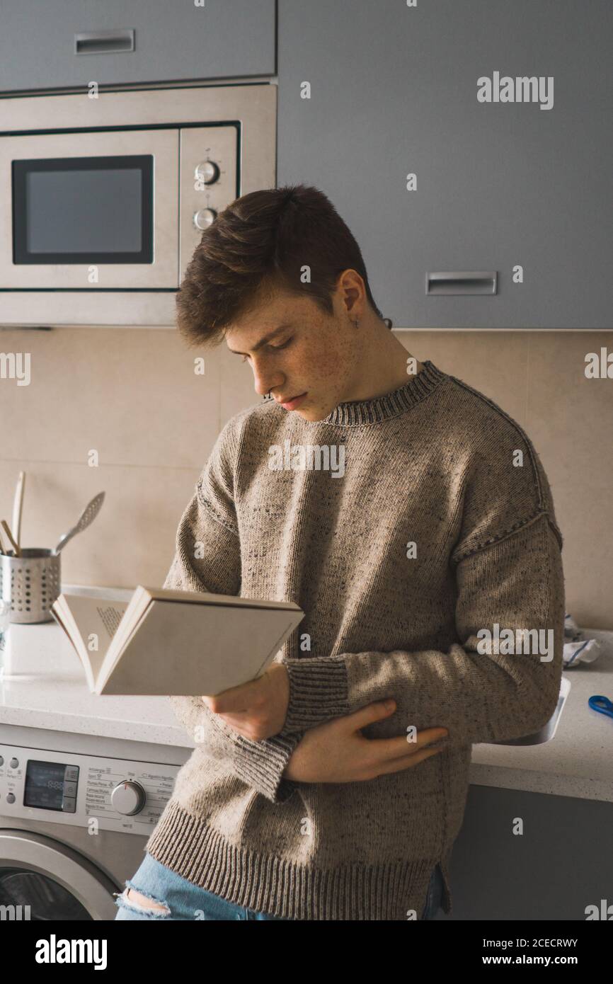 Homme décontracté lisant le livre dans la cuisine Banque D'Images