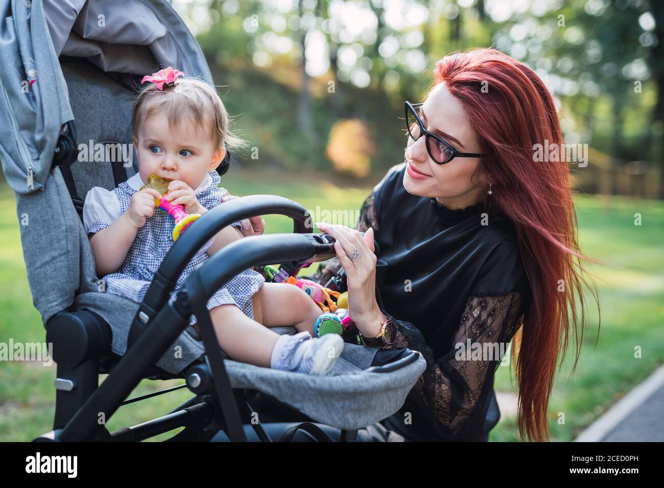 Belle Femme Aux Cheveux De Gingembre Souriant Et Regardant Adorable Bebe Fille Avec Jouet En Caleche Sur Fond Flou Du Parc Photo Stock Alamy Belle Femme Aux Cheveux De Gingembre Souriant Et Regardant Adorable Bebe Fille Avec Jouet En Caleche Sur Fond Flou Du Parc Photo Stock Alamy