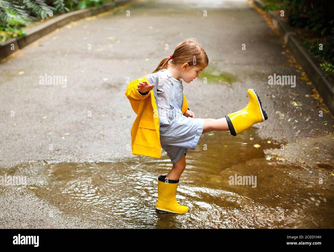 Petite Fille En Imperméable Jaune Court Sur Un Chemin De Terre Avec Des  Boules Et De La Boue Image stock - Image du lifestyle, nature: 244286961