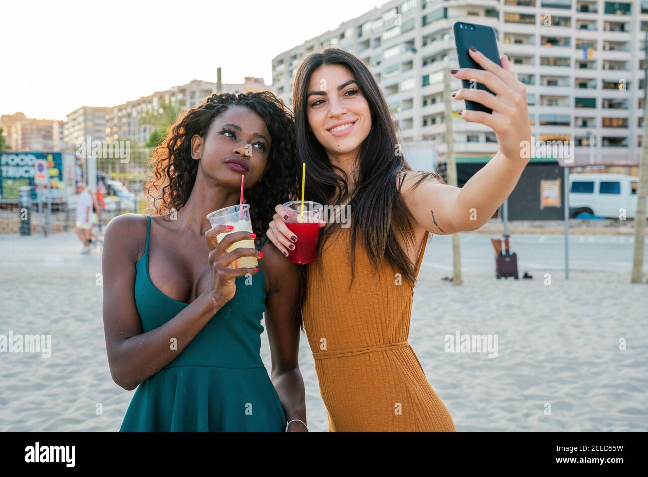 Des femmes élégantes et variées avec des boissons prenant le selfie sur la plage Banque D'Images