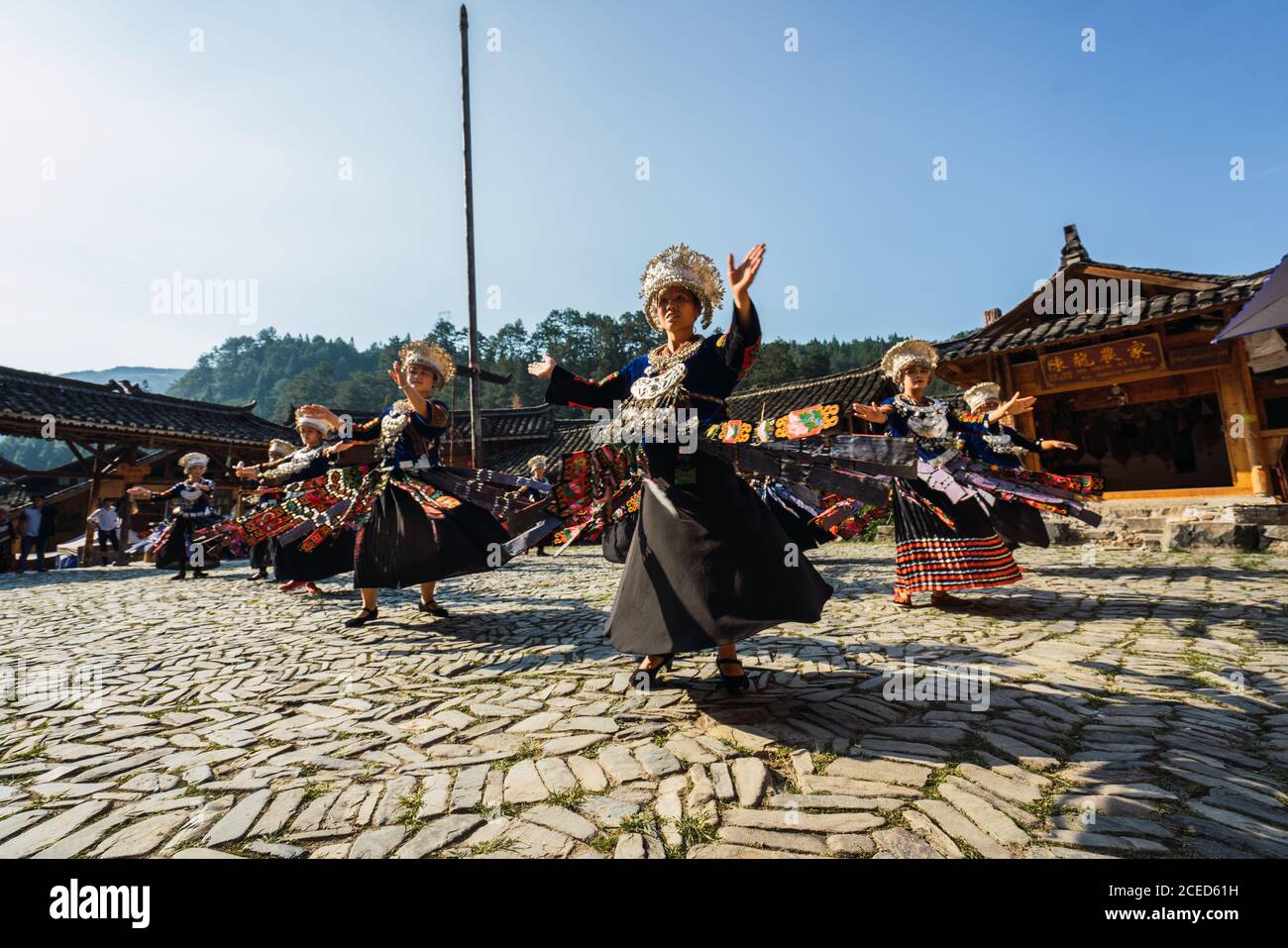 GUINZHOU, CHINE - 14 JUIN 2018 : les femmes du groupe ethnique Miao en costumes clairs avec des ornements colorés et des coiffes effectuant la danse traditionnelle du festival sur la place du village le jour ensoleillé de l'été dans la province de Guizhou en Chine Banque D'Images