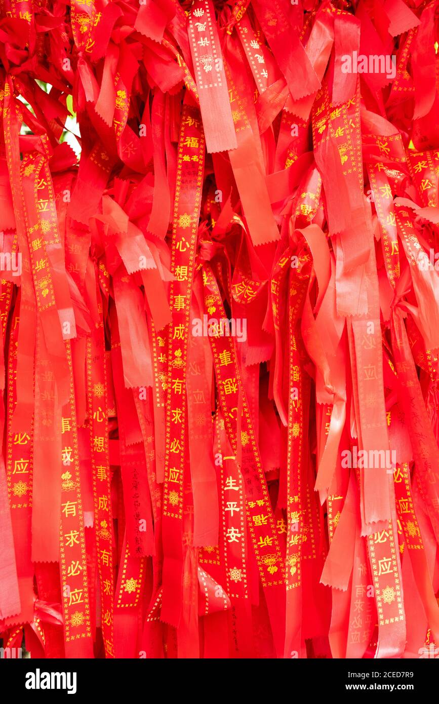 Arrière-plan sans couture de rubans de souhaits rouge vif avec hiéroglyphes chinois dorés en gros plan, île de Wuzhizhou Banque D'Images