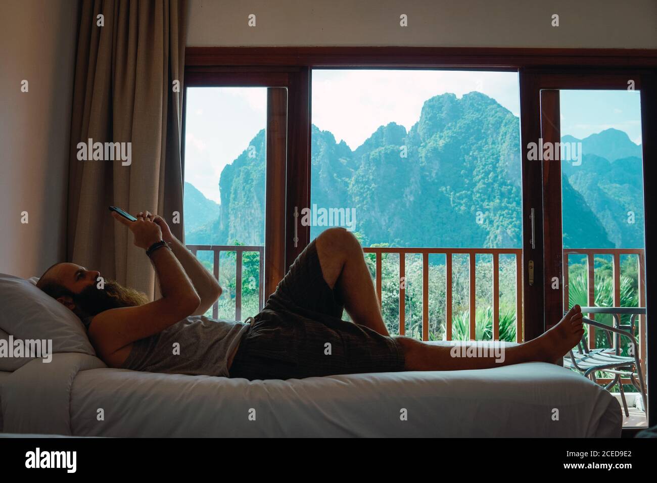 homme se reposant sur un lit avec un smartphone à la maison Banque D'Images