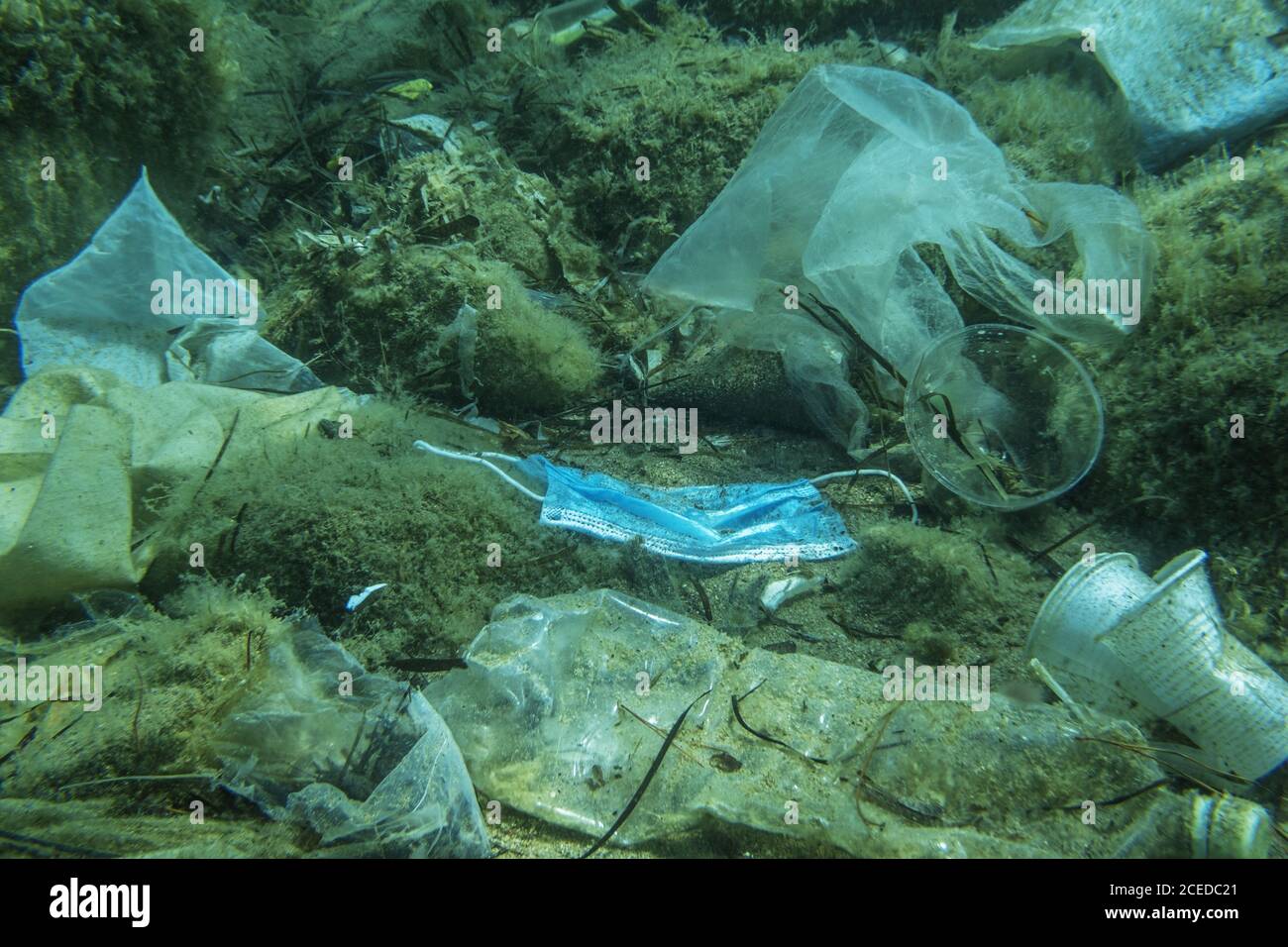 Le masque médical usagé ainsi que d'autres débris de plastique se trouvent sur le fond marin. Banque D'Images