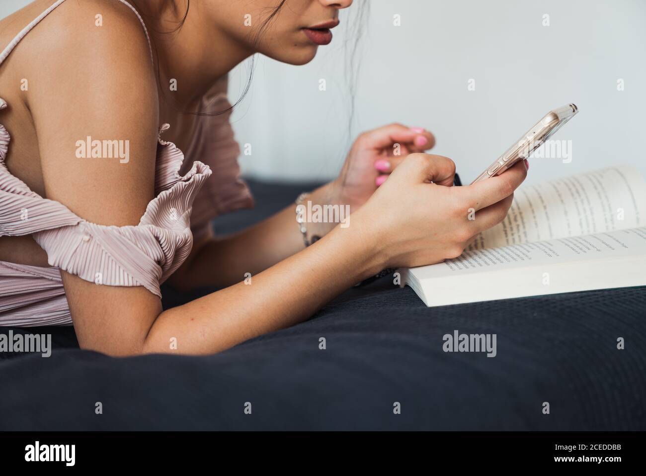 Femme avec livre et smartphone se refroidissant sur le lit Banque D'Images