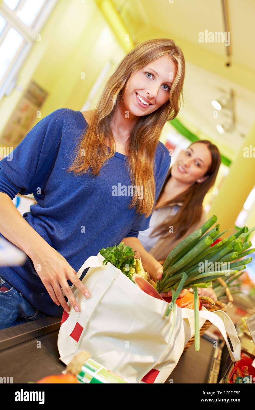 Femme souriante avec un sac à provisions complet à la caisse du supermarché Banque D'Images