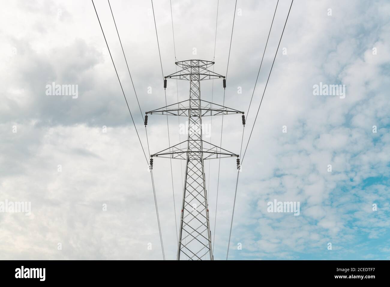 Ligne de transmission de puissance triphasée à circuit unique, tour en treillis d'acier ou pylône d'électricité contre les nuages blancs au ciel Banque D'Images
