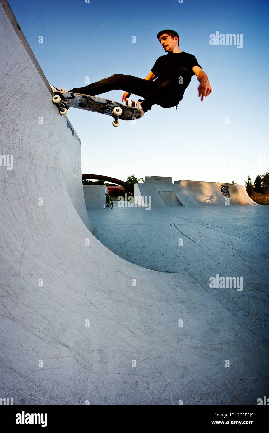 Un petit garçon fait du skateboard dans un parc de skate l'après-midi Banque D'Images