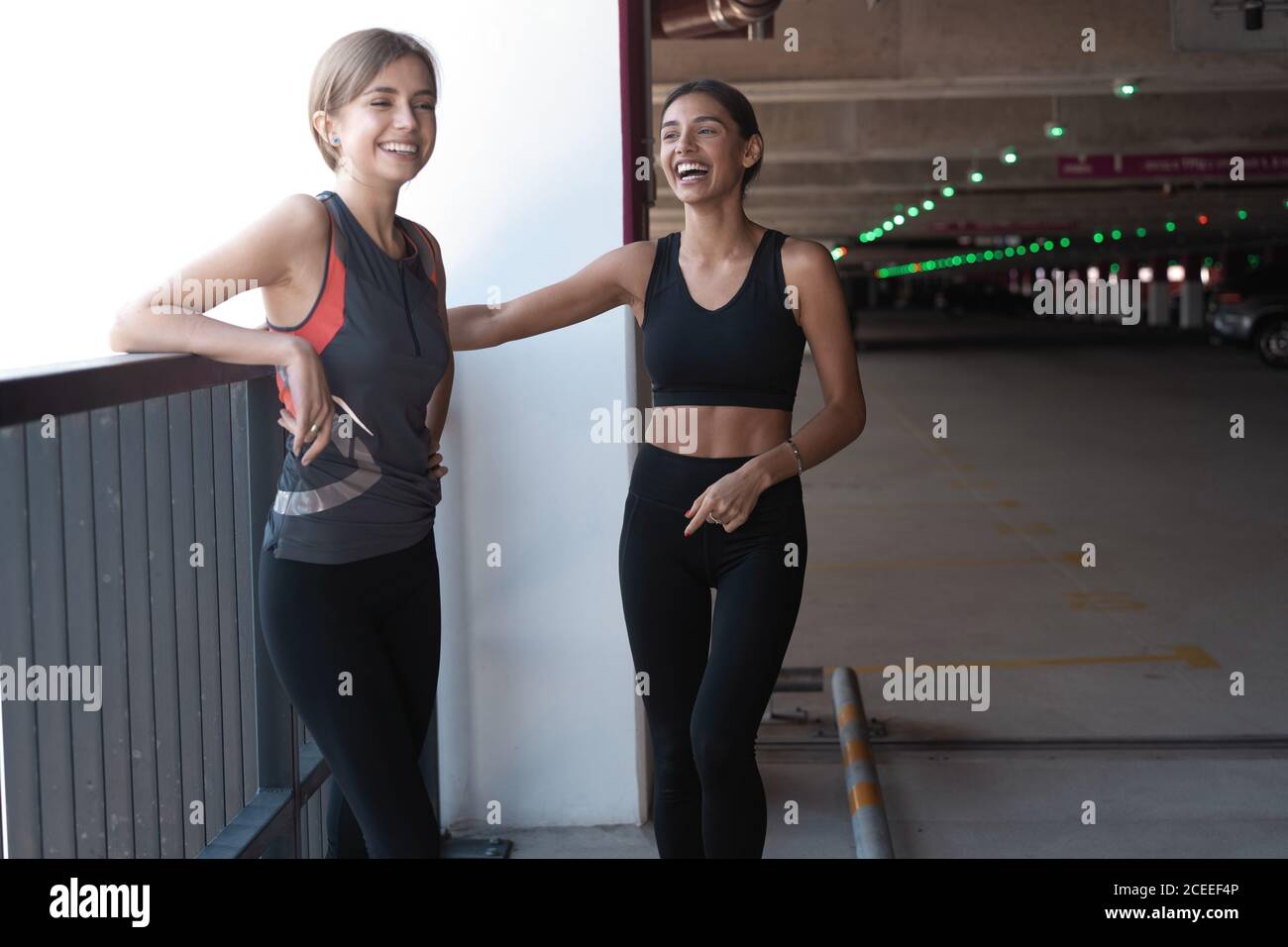 Deux jeunes femmes athlétiques souriantes qui marchent ensemble à l'extérieur après un entraînement sportif, qui parlent et s'embrasent les unes les autres. Banque D'Images