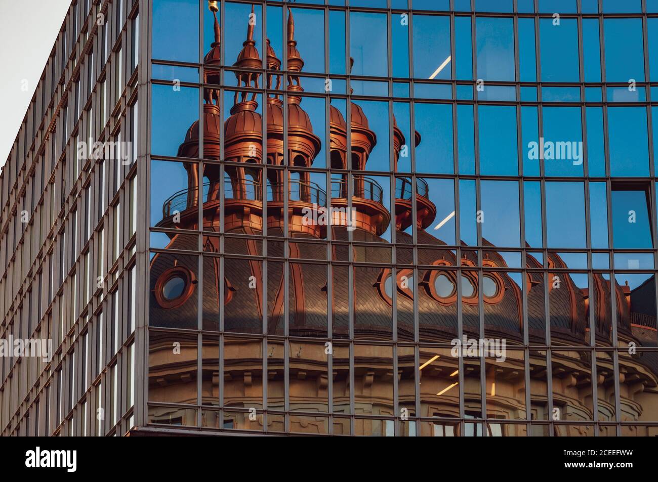 Reflet du toit de la chapelle dans un mur miroir. Distorsion de la réflexion dans les fenêtres en verre. Extérieur du bâtiment d'entreprise avec fenêtres panoramiques en verre bleu Banque D'Images