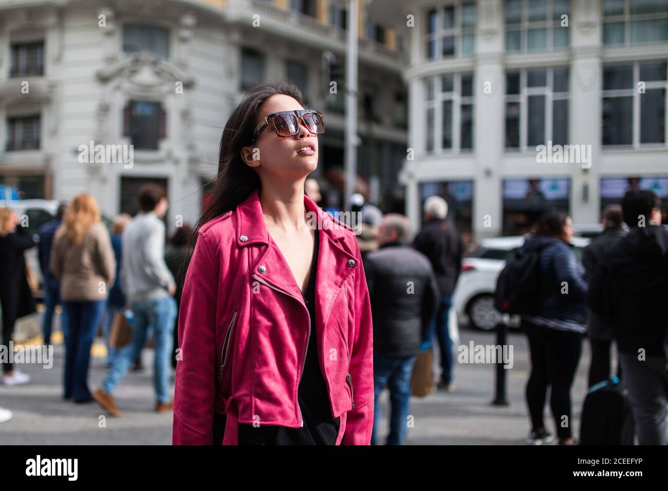 Femme moderne tendance portant une veste en cuir rose avec lunettes de  soleil et debout dans la rue au soleil Photo Stock - Alamy