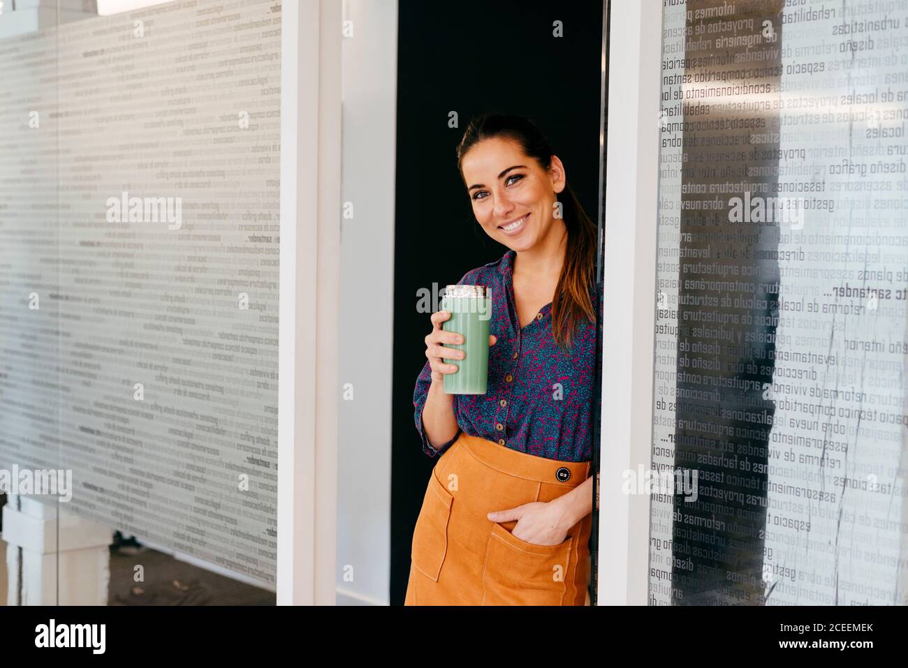 Femme souriante avec une tasse au bureau Banque D'Images