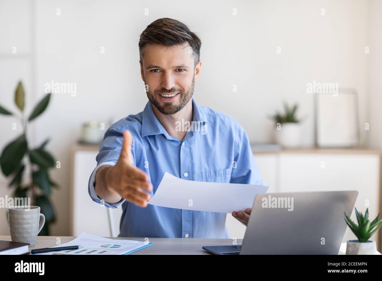 Entrevue d'emploi. Un responsable RH sympathique, homme, se tient à la main pour se faire une poignée de main à l'appareil photo Banque D'Images