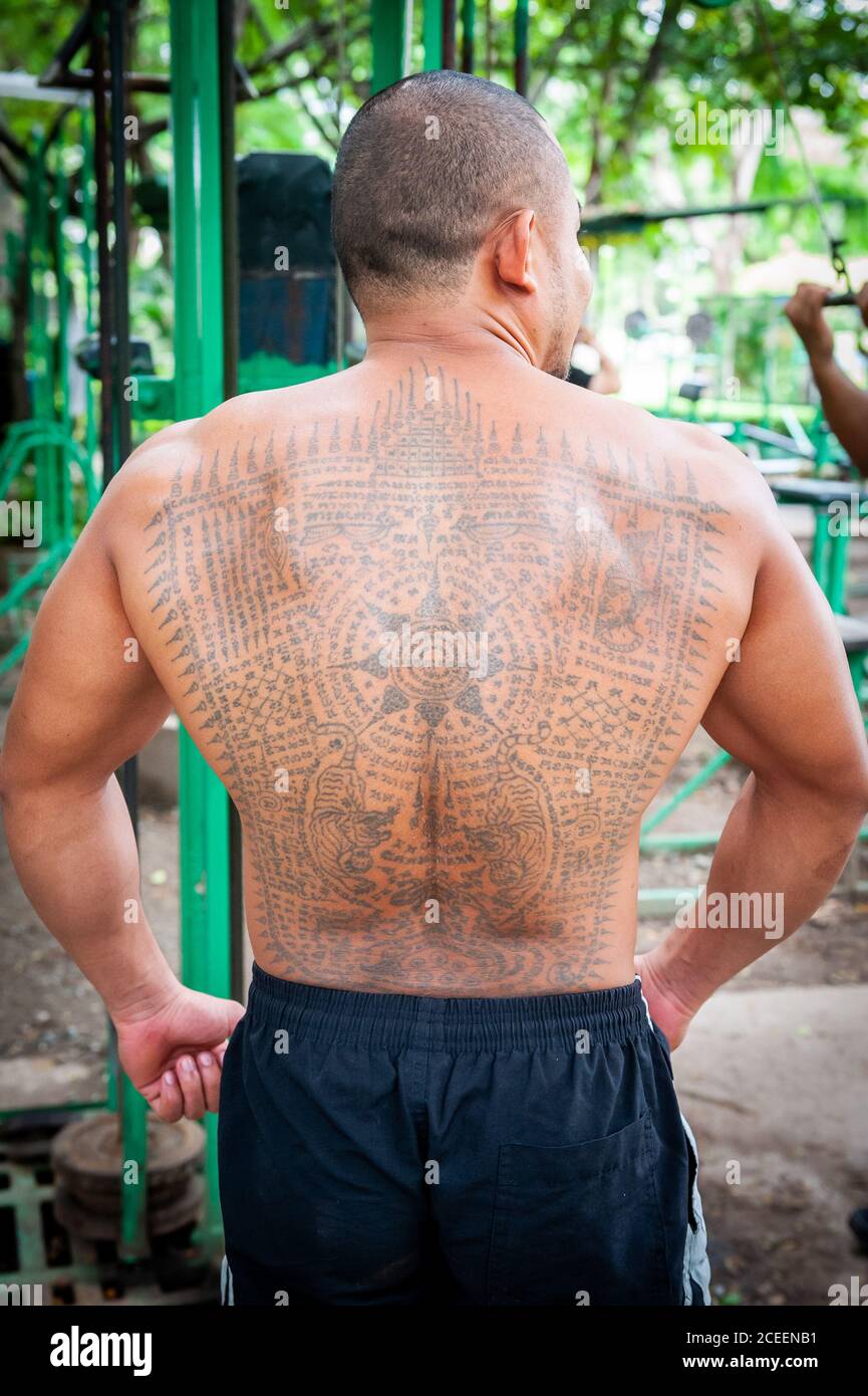 Des hommes thaïlandais locaux s'entraîner dans la salle de sport en plein air du parc Lumphini Bangkok Thaïlande. Ce jeune homme thaïlandais présente quelques tatouages bouddhistes thaïlandais impressionnants. Banque D'Images