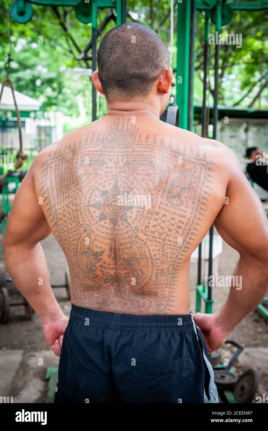 Des hommes thaïlandais locaux s'entraîner dans la salle de sport en plein air du parc Lumphini Bangkok Thaïlande. Ce jeune homme thaïlandais présente quelques tatouages bouddhistes thaïlandais impressionnants. Banque D'Images