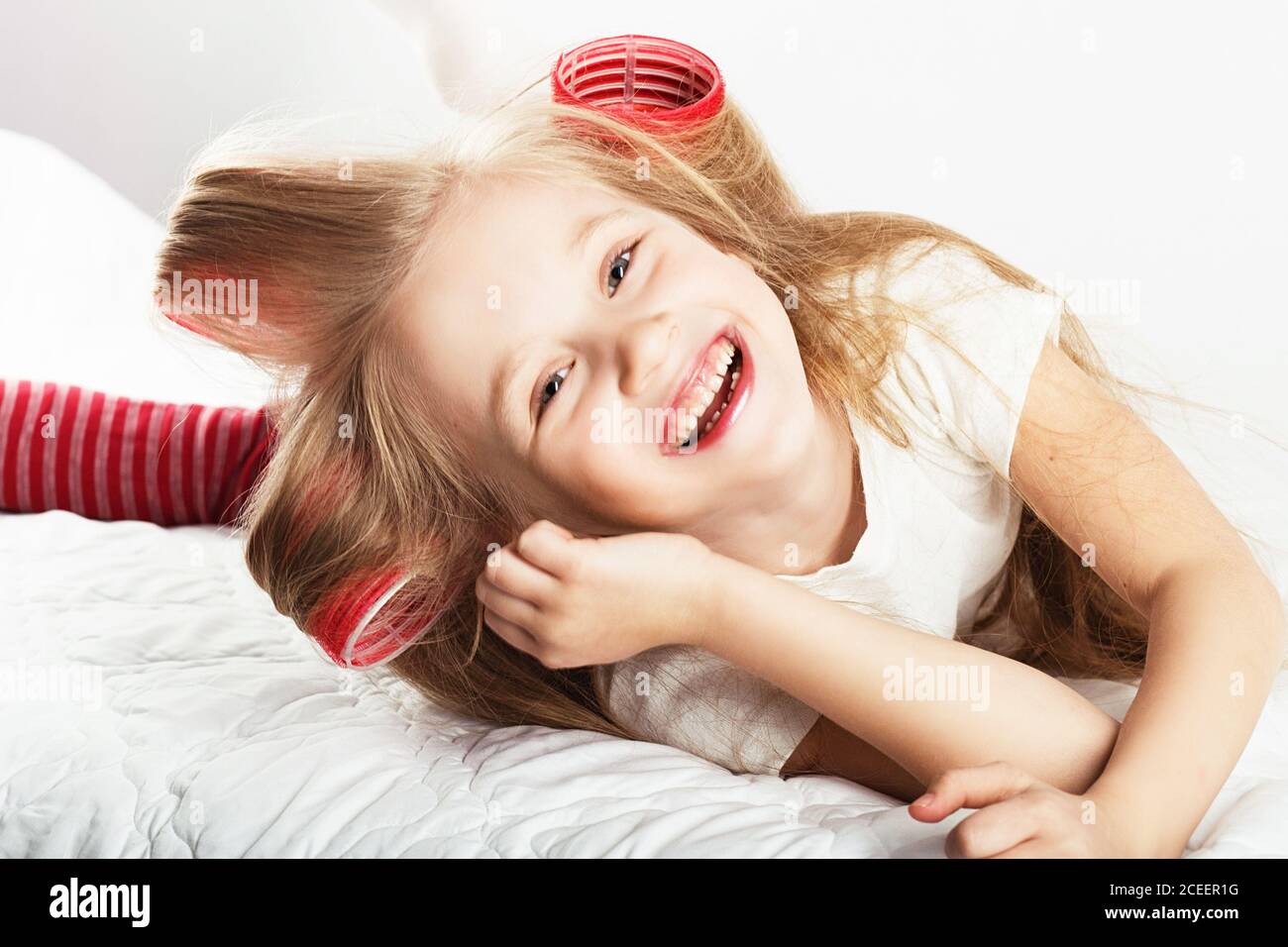 Belle Petite Fille Avec Des Boucles Sur Sa Tete Regardant L Appareil Photo Et S Amuser A La Maison Jour De Conge Vacances Jour De Repos Gratuit Hors Temps Mode Bebe G Photo Stock