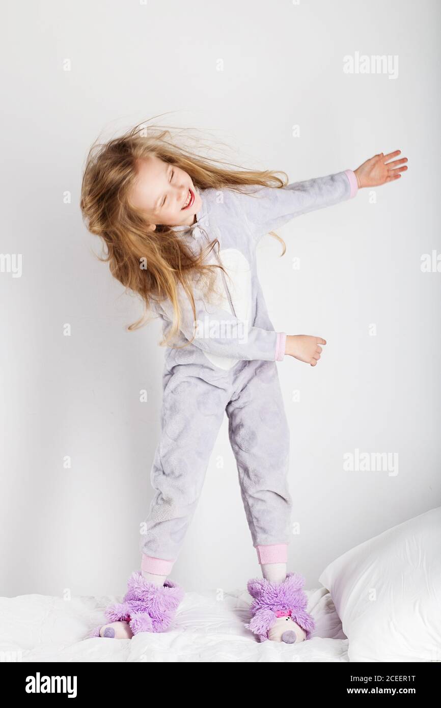 Petite fille drôle en pyjama sautant et ayant du plaisir dans le lit à la  maison. Fête de pyjama, jour de congé, vacances, jour de repos, gratuit,  hors-temps Photo Stock - Alamy