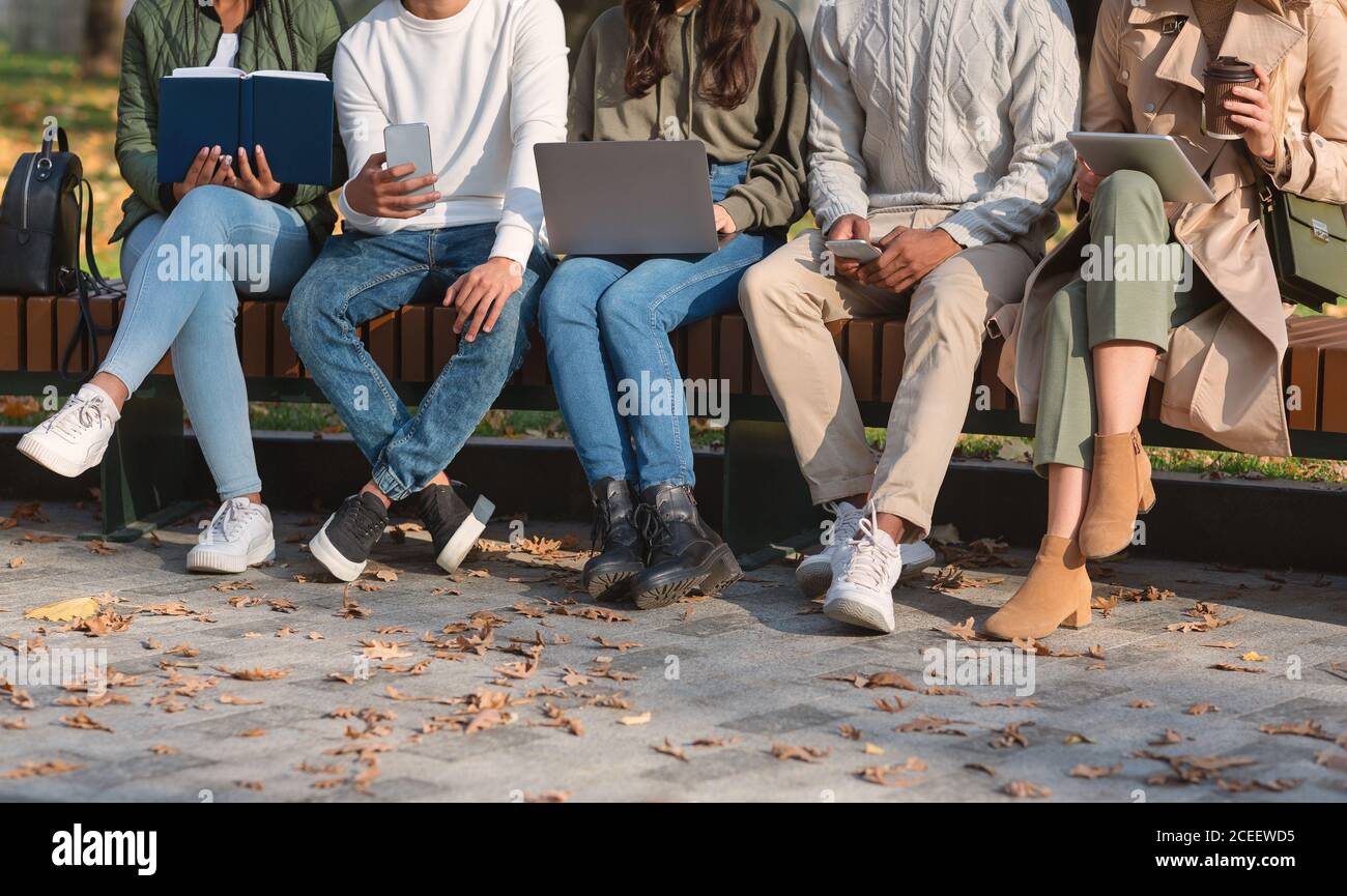 Groupe d'étudiants assis au banc dans le parc et étudiant Banque D'Images