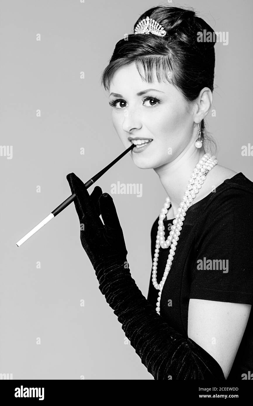 Portrait d'une belle jeune femme de style rétro avec une cigarette dans un  porte-parole à l'image de la célèbre actrice Audrey Hepburn. Pho noir et  blanc Photo Stock - Alamy