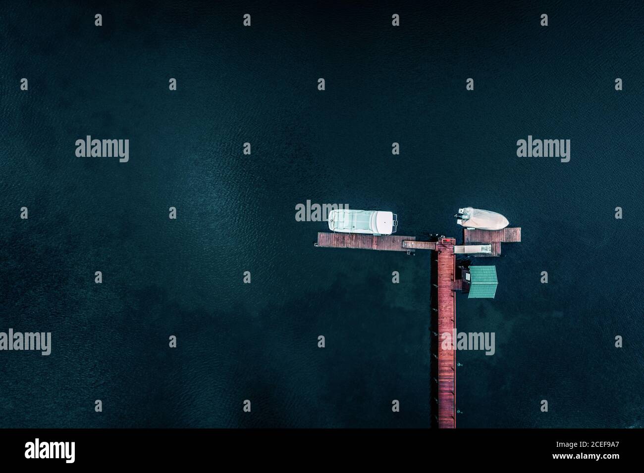 Vue aérienne des petits bateaux amarrés à la plate-forme d'atterrissage en bois entouré par la belle surface d'eau sombre et profonde de l'océan Banque D'Images