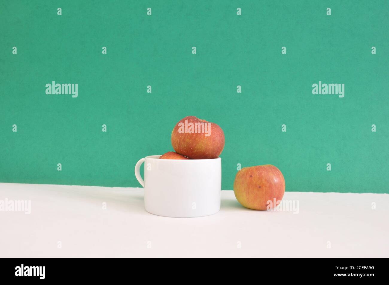 Pommes dans une tasse blanche avec une pomme isolée concept de séparation d'arrière-plan vert Banque D'Images