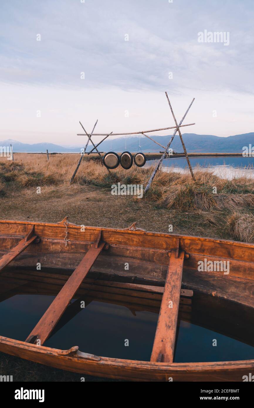Vue sur le vieux bateau en bois rempli d'eau par temps froid rive avec construction en bois et disques métalliques Banque D'Images