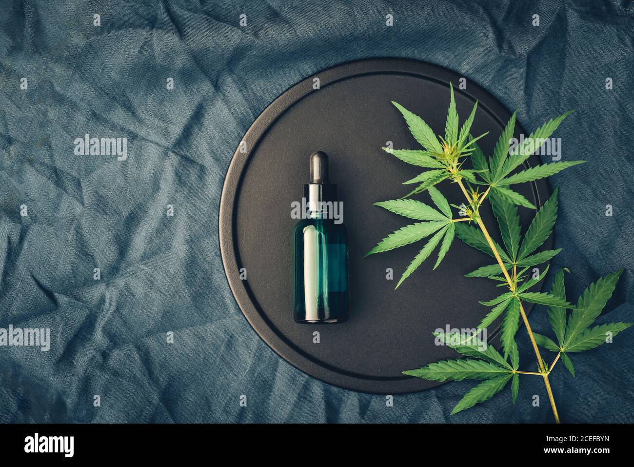 Cannabis produit médical, huile de CBD, avec des feuilles de chanvre sur un plat noir Banque D'Images