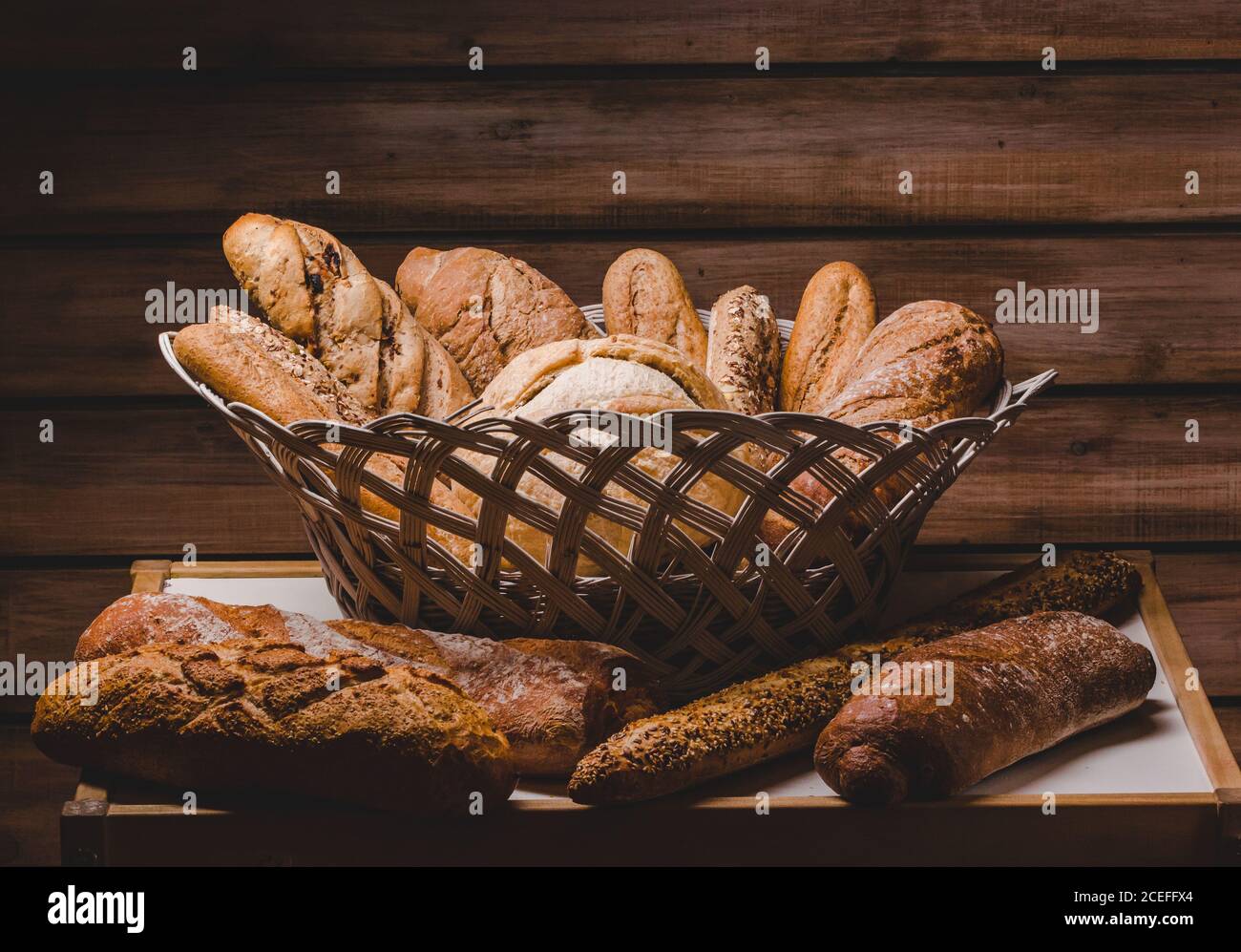 Magnifique arrangement rustique de panier avec pains et petits pains et baguettes sur fond de bois. Banque D'Images